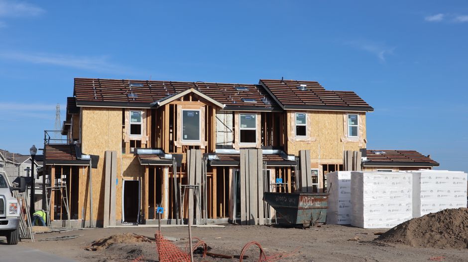 Front view of a two-story house under construction with clear blue skies.