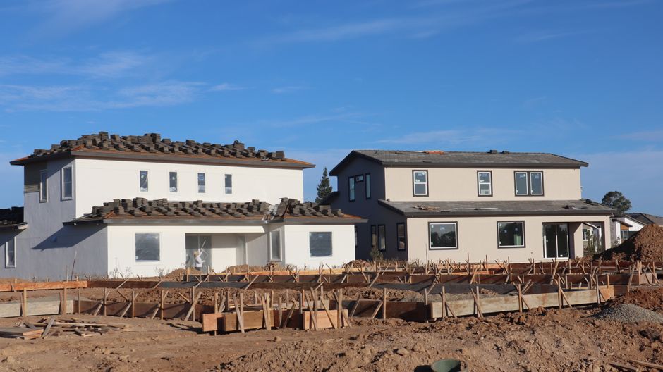 Row of newly built houses with large windows under a clear sky.